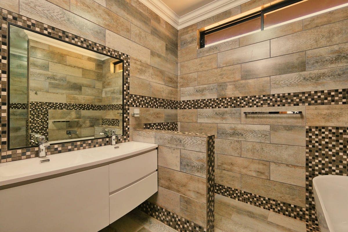 Rivestimento a mosaico e piastrelle effetto legno sopra un mobile da bagno