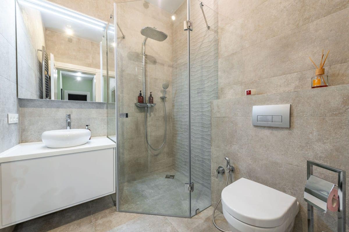 Bagno con box doccia in cristallo, sanitari e pavimento piastrellato