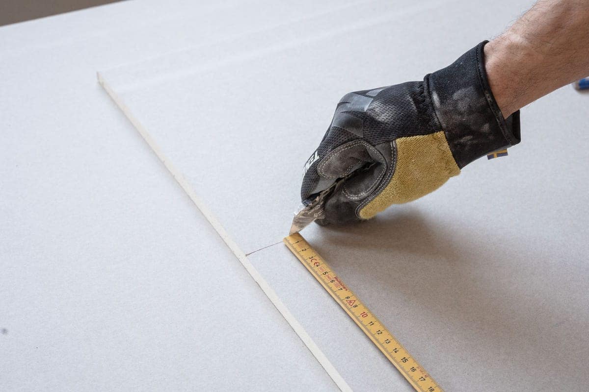 Taglio di una lastra di cartongesso con cutter e metro